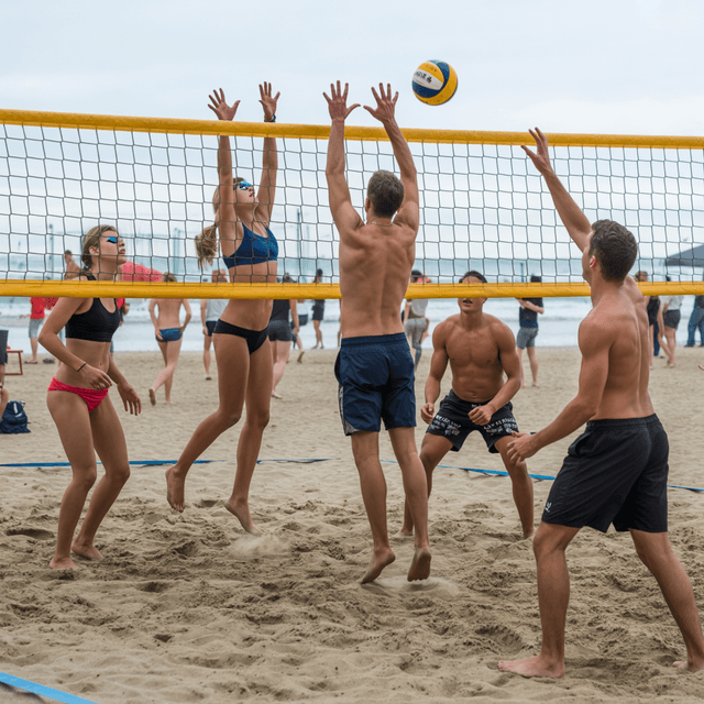 Players diving for a volleyball on a beach court